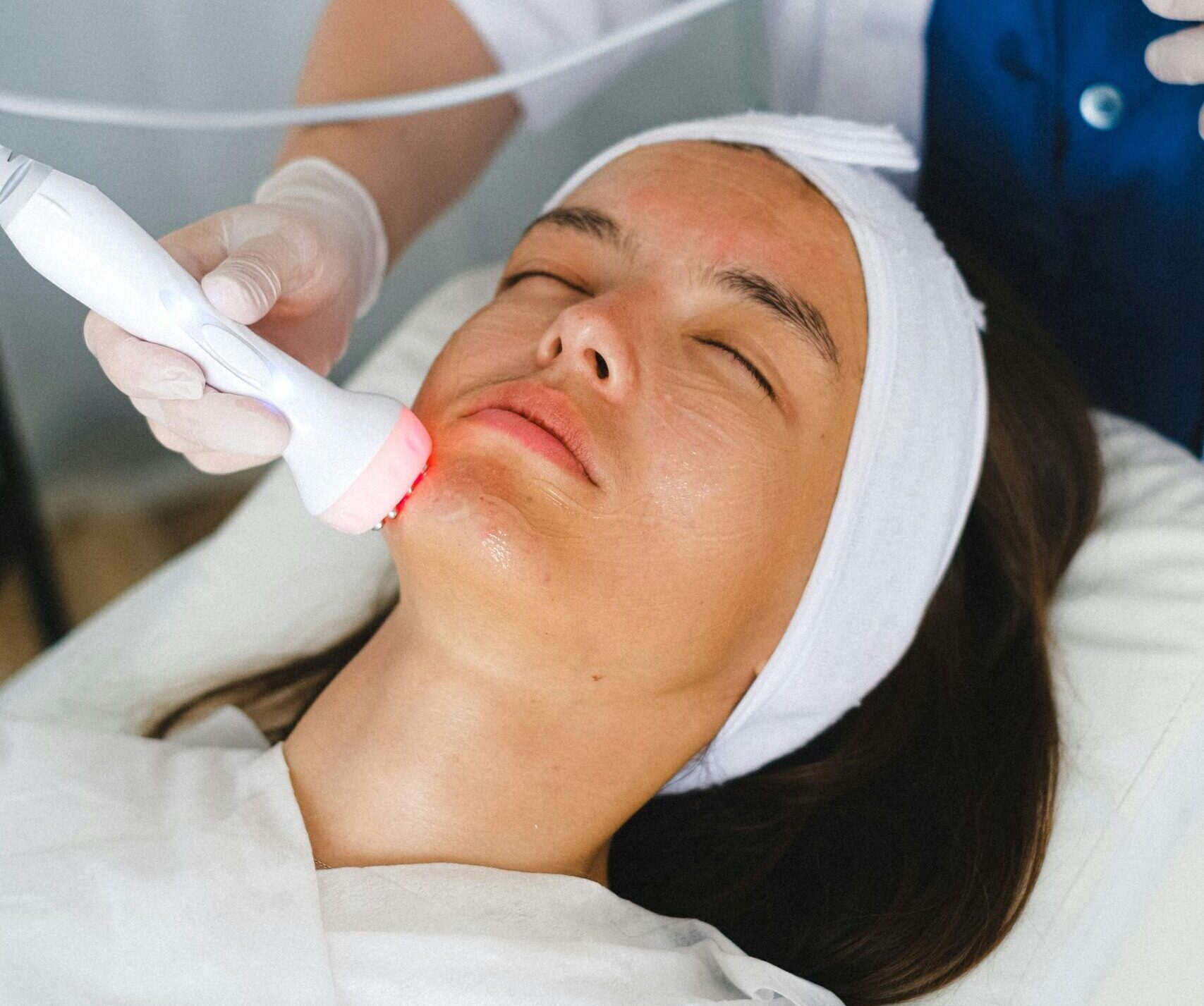 High angle of crop female cosmetician with modern professional tool treating face of woman during cosmetic procedure